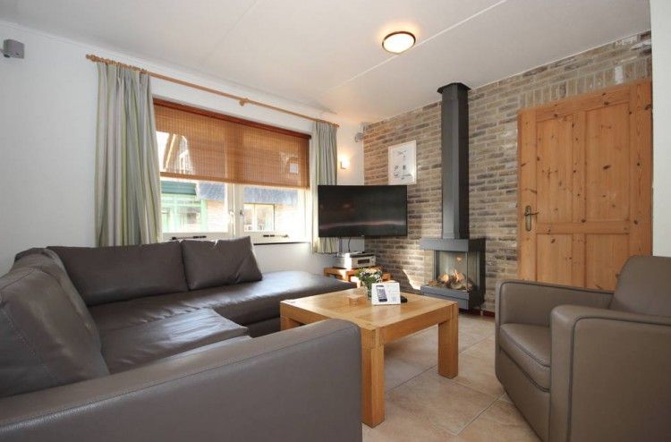 Gezellige woonkamer in de 6 pers. luxe villa met serre, De Cocksdorp, Texel, met open haard voor een knusse vakantie.