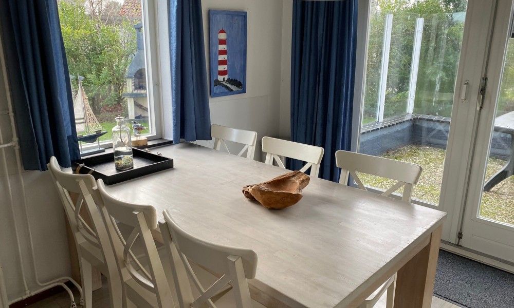 Gemuetliches Esszimmer in Krim 661 mit Sauna, Stuha und Grill, ein Bungalow in De Cocksdorp, Texel, mit Blick auf den gruenen Garten.