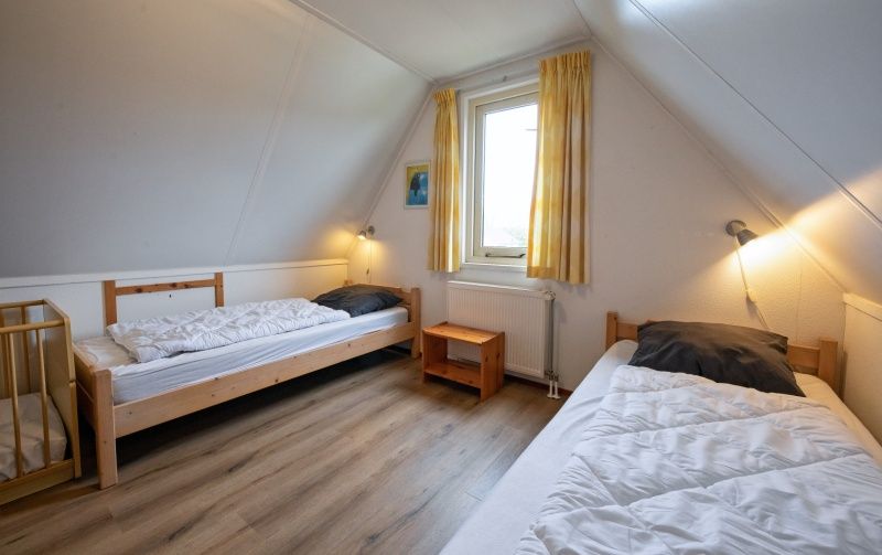 Geraeumiges Schlafzimmer im Ferienhaus Schelpenoord 129, De Cocksdorp, Texel mit zwei Einzelbetten.