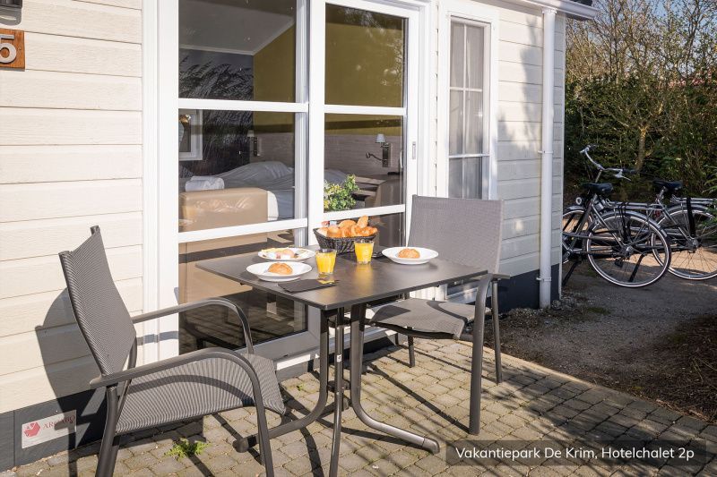 Fruehstueck auf der Terrasse des luxurioesen 2-Personen-Hotelchalets in De Cocksdorp, Texel, mit Blick auf die ruhige Umgebung.