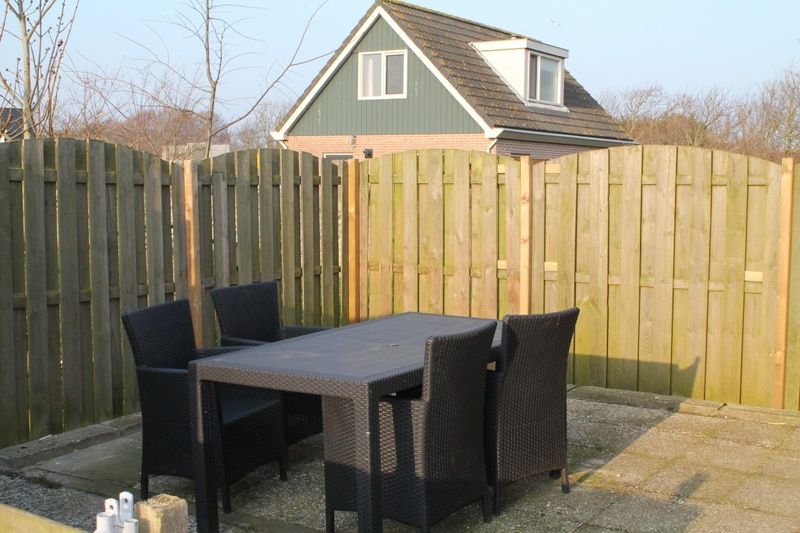Gemuetliche Terrasse am Ferienhaus Onder de vuurtoren 115, De Cocksdorp, Texel fuer Mahlzeiten im Freien.