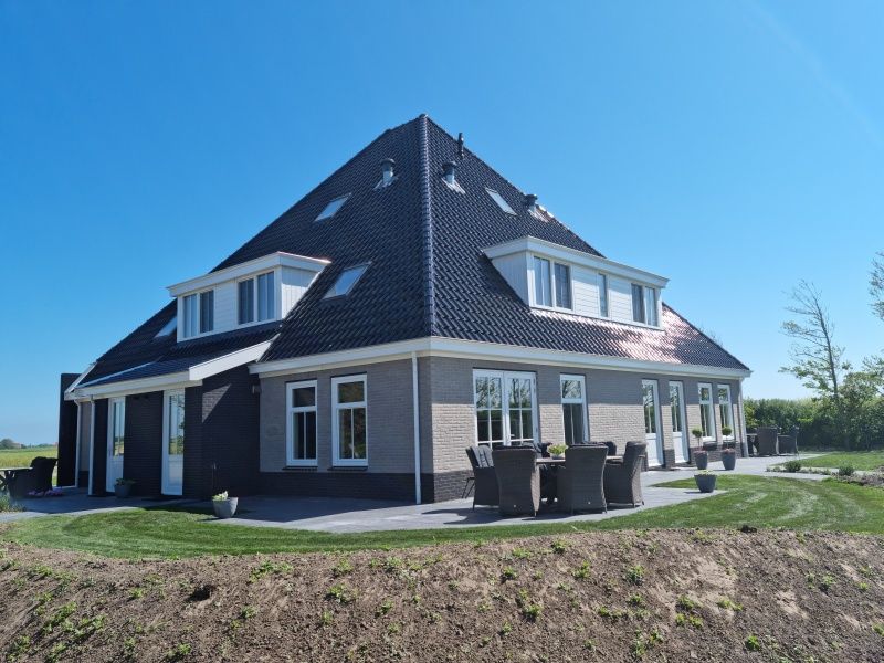 Seitenansicht des Ferienhauses De Slufter auf Texel, mit gemuetlichen Sitzecken im Freien.