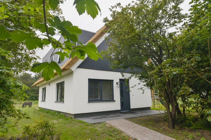 Eingang zum Ferienhaus De Postschipper in De Cocksdorp, Texel, umgeben von Gruenanlagen.