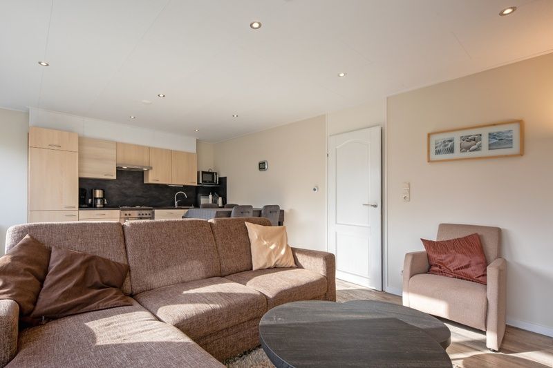 Offener Wohnbereich im Ferienhaus Slufterhoek 102, De Cocksdorp, Texel mit einer gemuetlichen Sitzecke und Blick auf die Kueche.