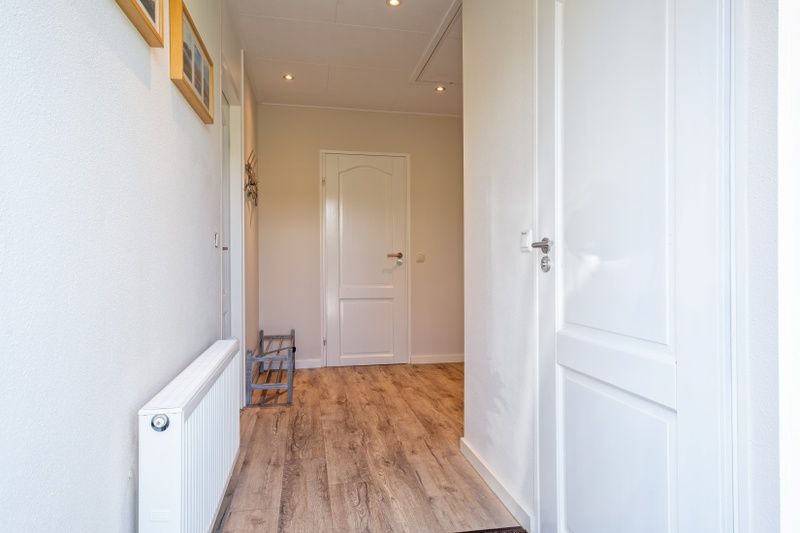 Heller Flur im Ferienhaus Slufterhoek 102, De Cocksdorp, Texel mit Holzboden und Zugang zu mehreren Raeumen.