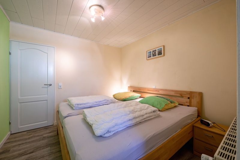 Schlafzimmer im Ferienhaus Slufterhoek 102, De Cocksdorp, Texel mit Doppelbett und warmer Beleuchtung fuer eine beruhigende Atmosphaere.