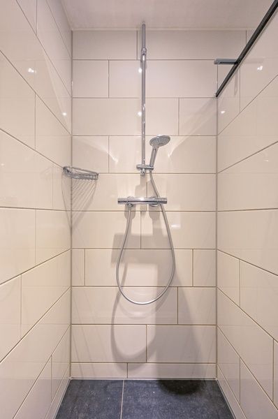 Moderne Dusche im Ferienhaus Slufterhoek 102, De Cocksdorp, Texel mit elegantem Duschkopf und weissen Wandfliesen.