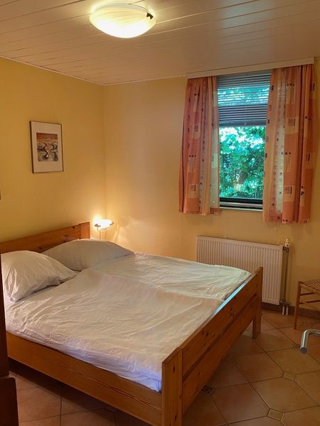 Zweites Schlafzimmer des Ferienhauses Slufterhoek 128 in De Cocksdorp Texel, mit grossem Fenster und Bett.