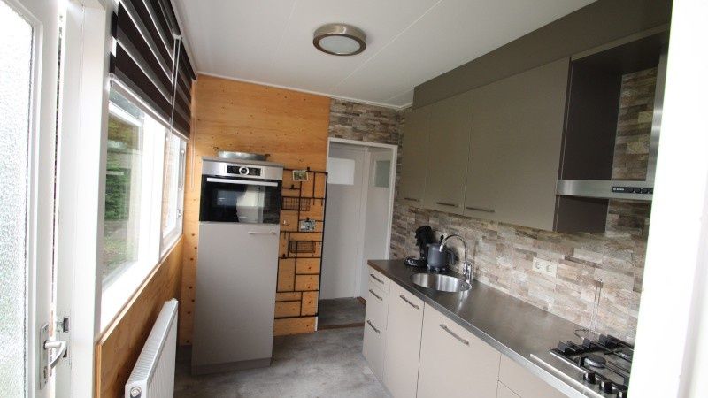 Stilvolle Kueche im Bungalow Tamarisk 164 - Bartje, De Cocksdorp, Texel mit Blick auf den Garten.