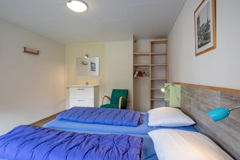 Geraeumiges Schlafzimmer im Bungalow Tamarisk 206, De Cocksdorp, Texel mit Sitzgelegenheit und Stauraum.