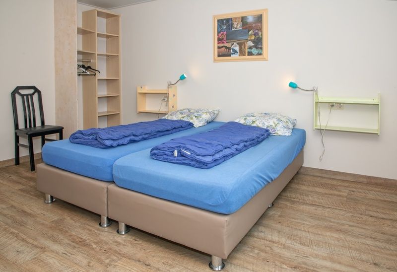 Zweites Schlafzimmer im Bungalow Tamarisk 206, De Cocksdorp, Texel mit Doppelbett und dekorativen Elementen.