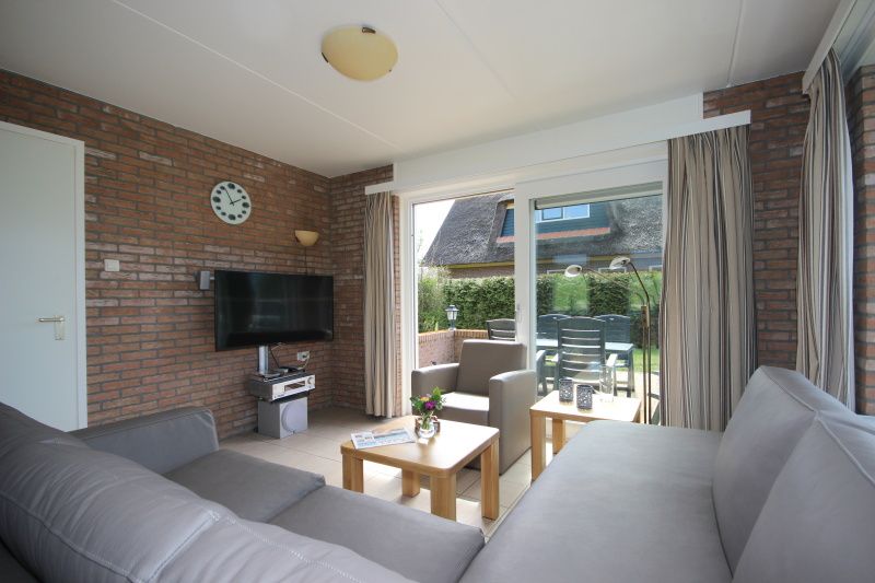 Gezellige woonkamer in Bungalow De Witte Hoek 6 Pers., De Cocksdorp, Texel met comfortabel interieur en tuinzicht.