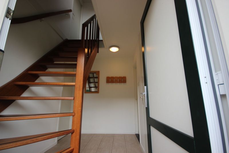 Houten trap in de hal van Bungalow De Witte Hoek 6 Pers., De Cocksdorp, Texel met toegang tot bovenverdieping.