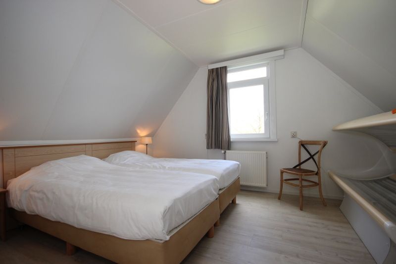 Zolderkamer in Bungalow De Witte Hoek 6 Pers., De Cocksdorp, Texel met twee bedden en veel natuurlijk licht.