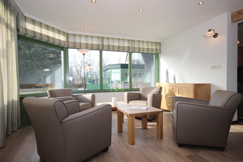 Helle Sitzecke im Wintergarten der Villa De Witte Hoek, Ferienhaus auf Texel mit Blick auf den Garten.