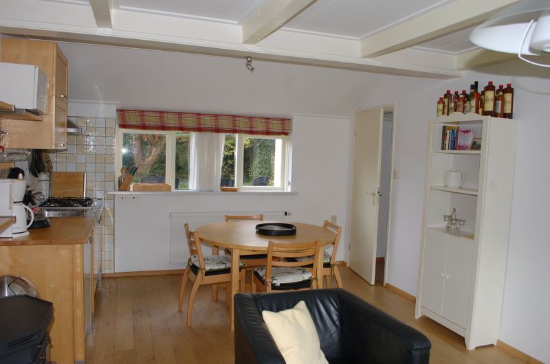 Dining area and kitchen in vacation home Kikkertstraat 067, De Cocksdorp, Texel, with wooden furniture.