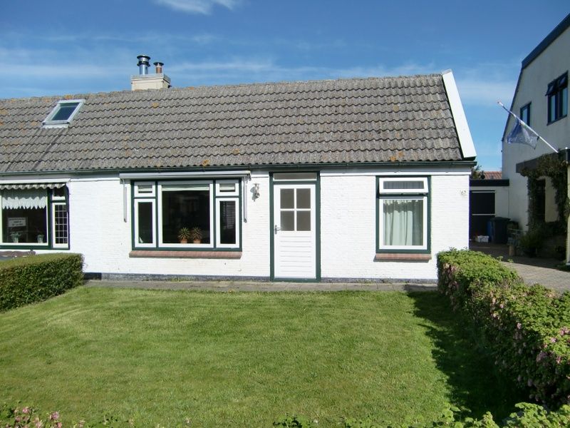 Front of vacation home Kikkertstraat 067, De Cocksdorp, Texel, with well-tended lawn.