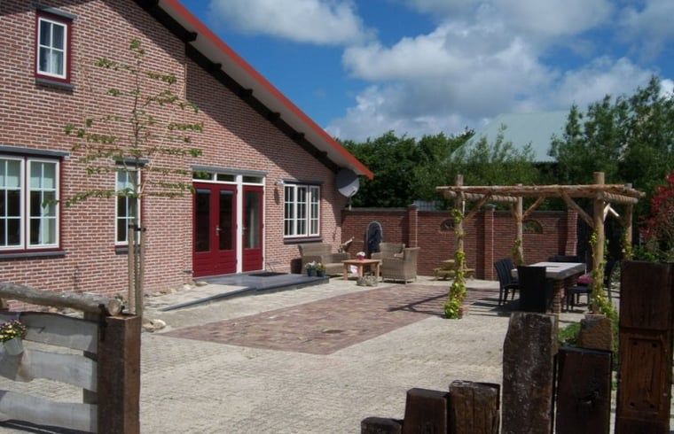 Charmante bakstenen gevel van Huisje in De Cocksdorp, Texel, met ruim terras voor ontspanning.