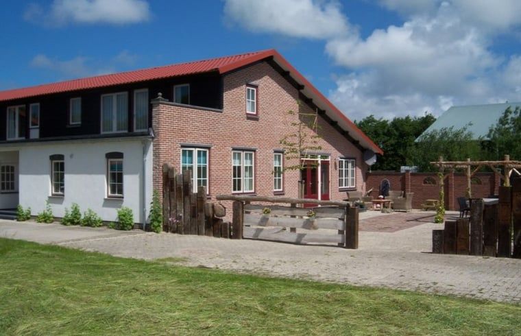 Ruime buitenruimte van vakantiehuis Huisje in De Cocksdorp, Texel, met groene omgeving.