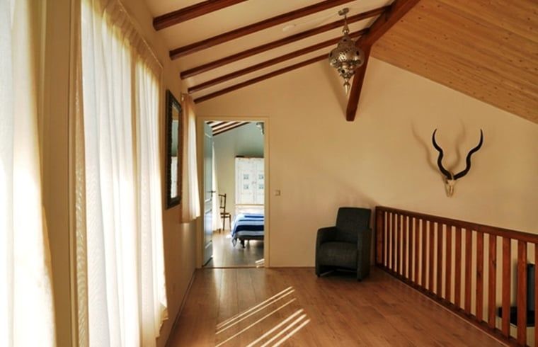 Zonnige hal op de bovenverdieping van Huisje in De Cocksdorp, Texel, met houten details.