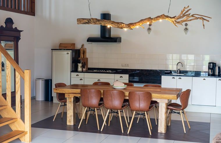 Stijlvolle eetkamer in Huisje in De Cocksdorp, Texel, met houten tafel en moderne keuken.