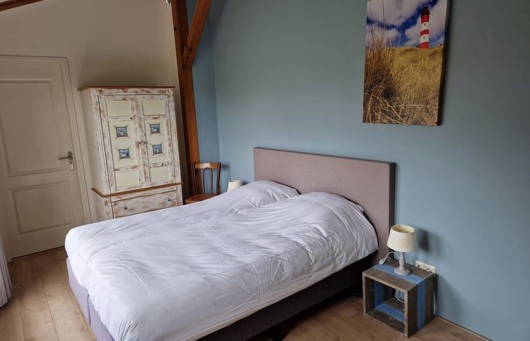 Slaapkamer in Huisje in De Cocksdorp, Texel, met schilderij van vuurtoren en landelijke stijl.