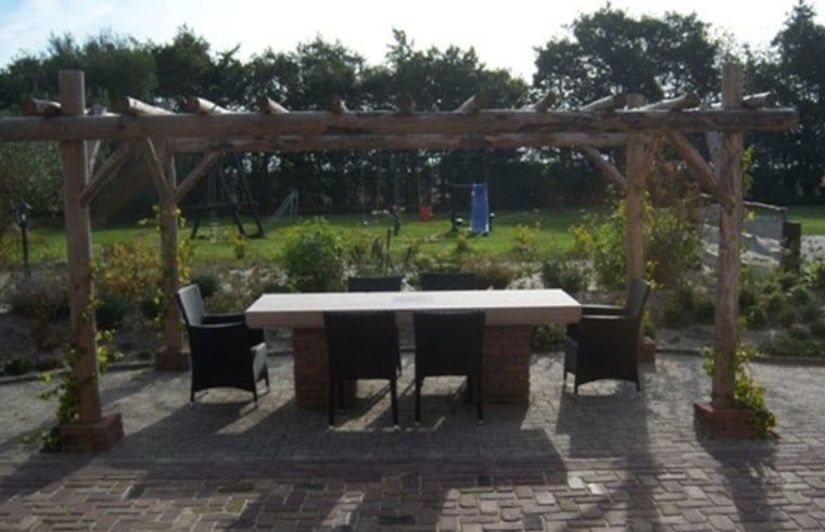 Buitenruimte van Huisje in De Cocksdorp, Texel, met pergola en gezellige zitplek.