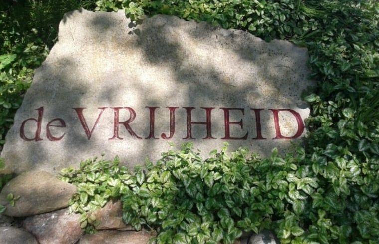 Welkomssteen bij Huisje in De Cocksdorp, Texel, met inscriptie 'de VRIJHEID' omgeven door groen.