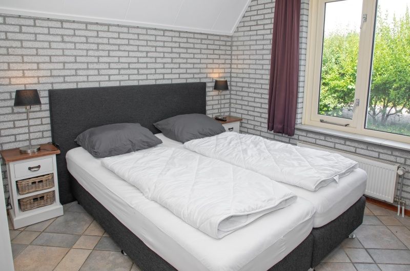 Bedroom with double bed in Holiday home Schelpenoord 121, De Cocksdorp Texel, offers a quiet atmosphere.