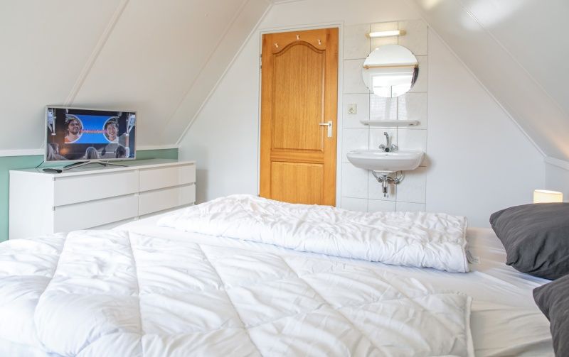 Bright bedroom with TV and sink in Holiday home Schelpenoord 121, De Cocksdorp Texel.