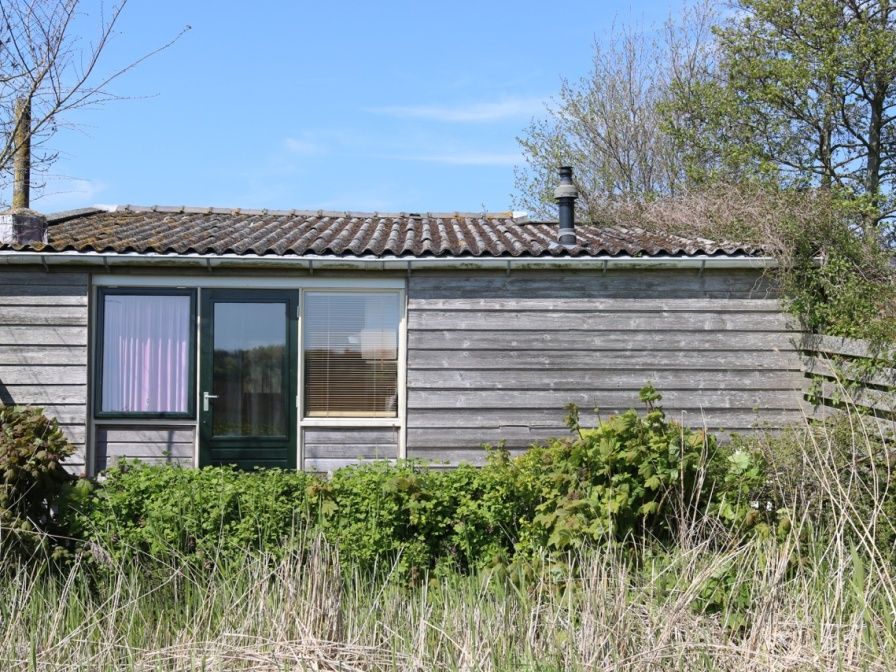 Rustikales Holzferienhaus Kikkertstraat 60 in De Cocksdorp, Texel, umgeben von gruener Natur.