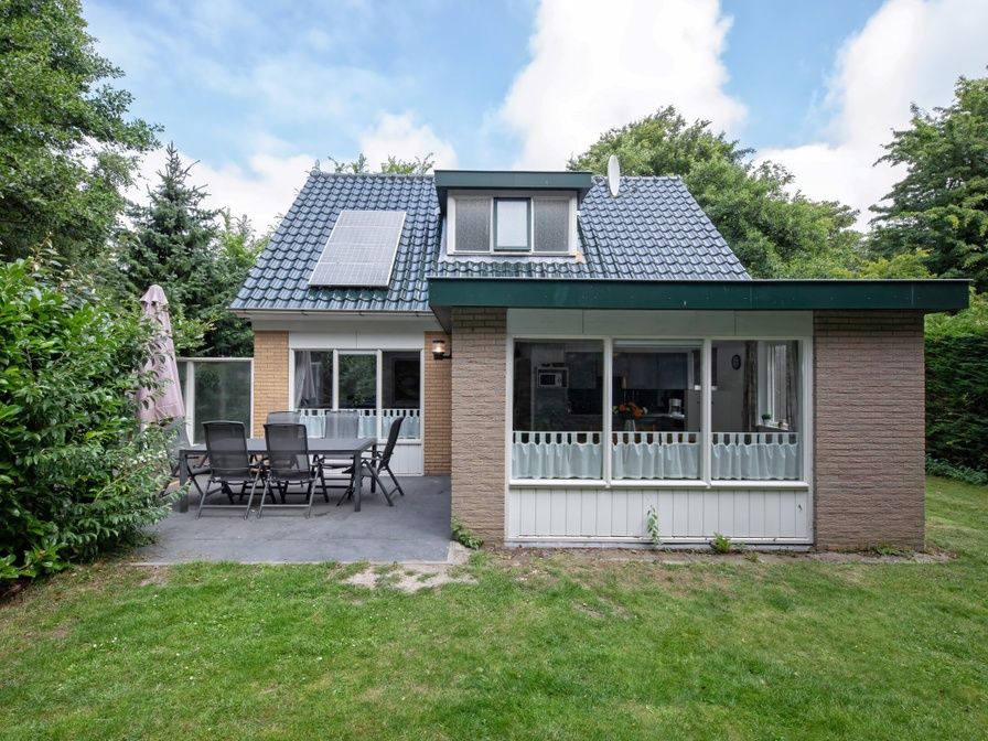 Aussenansicht des Ferienhauses Slufterduin 098 in De Cocksdorp, Texel, mit grosser Terrasse und gruener Umgebung.
