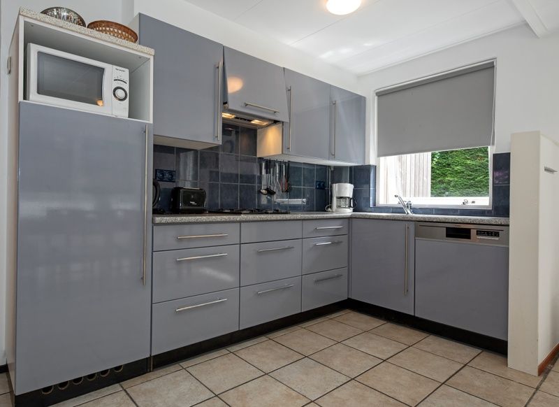 Moderne Kueche des Ferienhauses Slufterduin 098 in De Cocksdorp, Texel, mit grauen Schraenken und komplett ausgestattet.