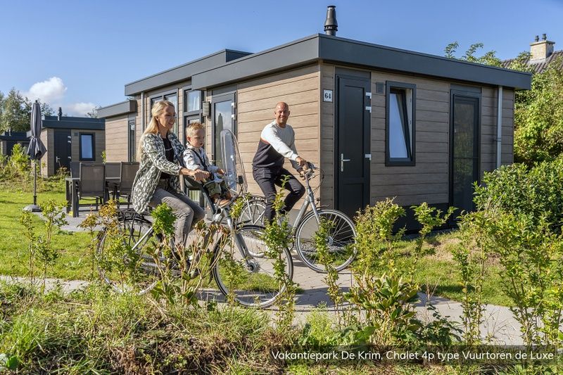 Die Familie radelt am Chalet Typ Vuurtoren de Luxe in De Cocksdorp auf Texel vorbei, umgeben von Natur.