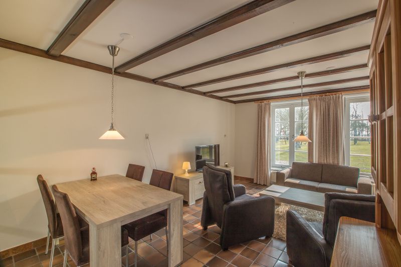 Gemuetliches Wohnzimmer im Ferienhaus Typ R, De Cocksdorp, Texel, mit Sitzecke und Gartenblick.