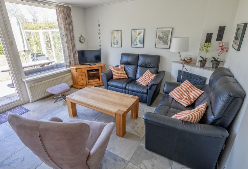 Gemuetliches Wohnzimmer des Ferienhauses Slufterhoek 078, Texel, mit bequemen Sofas und viel Licht.