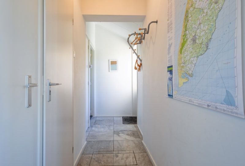 Eingang zum Ferienhaus Slufterhoek 078, De Cocksdorp, mit einer Karte von Texel an der Wand.