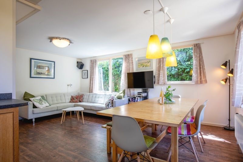 Gemuetliches Wohnzimmer des Ferienhauses Ganzenvlucht, De Cocksdorp, Texel, mit bequemer Sitzecke und Esstisch.