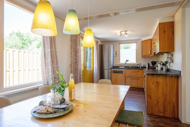 Stilvolle Essecke im Ferienhaus Ganzenvlucht, De Cocksdorp, Texel, mit Blick auf den Garten und die moderne Kueche.