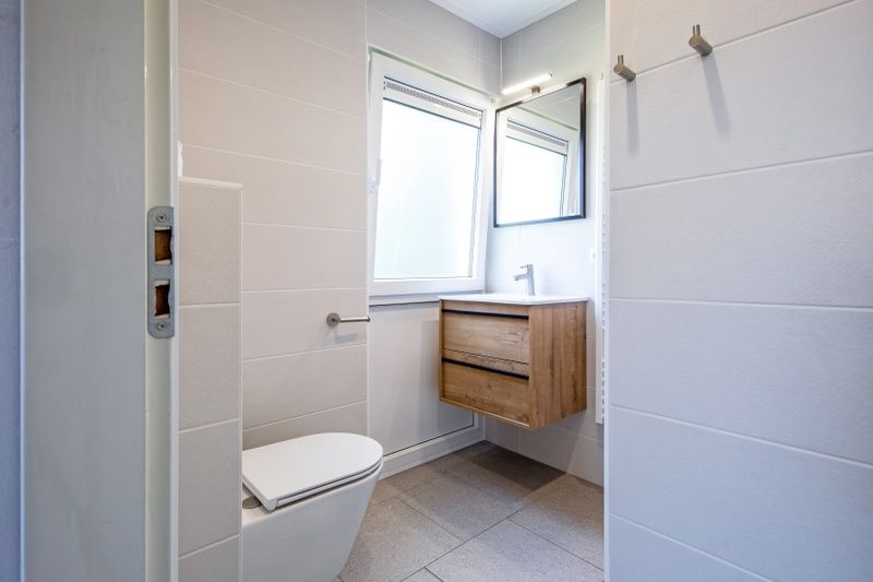 Modernes Badezimmer im Ferienhaus Slufterhoek 132, Texel, mit Toilette und stilvollem Waschbecken