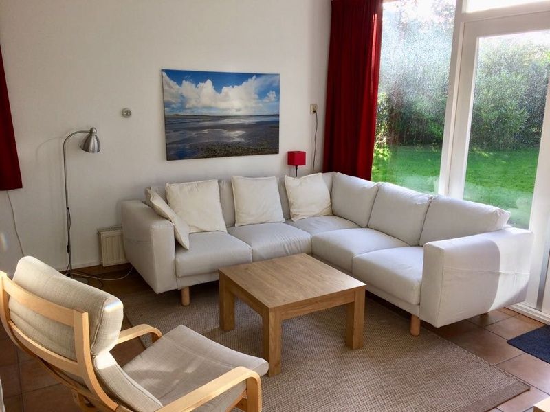 Gemuetliche Sitzecke im Bungalowpark Slufteroord, De Cocksdorp Texel, mit bequemem Sofa und Blick auf den gruenen Garten.