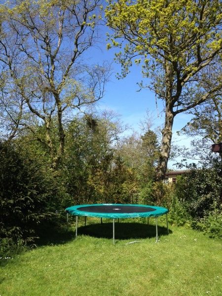 Geraeumiger Garten mit Trampolin im Ferienhaus Slufteroord 270, De Cocksdorp Texel, perfekt fuer Outdoor-Spass auf den Watteninseln.