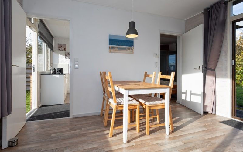 Dining area in Bungalow Tamarisk 190, a vacation home on Texel, with access to the kitchen.