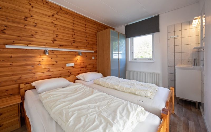 Bedroom with wooden accents in Bungalow Tamarisk 190, De Cocksdorp, Texel.