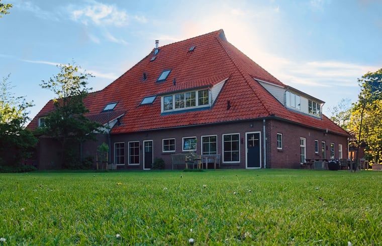 Hinterer Garten und Terrasse des Ferienhauses in De Cocksdorp, Texel, mit grossen Rasenflaechen.