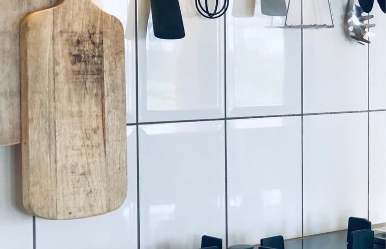 Kuechenzubehoer an der Wand im Ferienhaus in De Cocksdorp, Texel, mit Schneidebrettern und Utensilien.