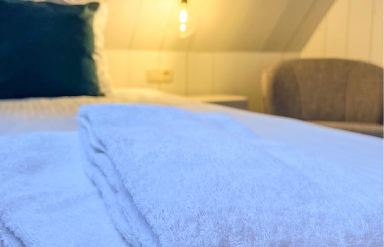 Detail des Bettzeugs im Ferienhaus in De Cocksdorp, Texel, mit weichen Handtuechern.