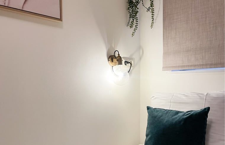Stimmungsvolle Wandleuchte im Schlafzimmer eines Ferienhauses in De Cocksdorp, Texel.