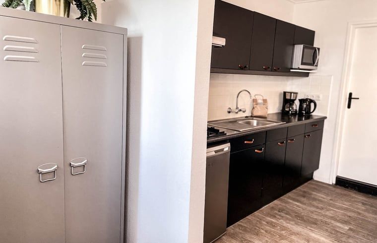 Moderne Kueche in einem Ferienhaus in De Cocksdorp, Texel, mit glatter Oberflaeche und Geraeten auf den Watteninseln.