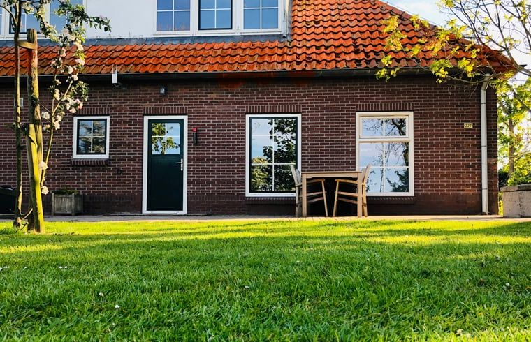 Terrasse des Ferienhauses in De Cocksdorp, Texel, mit Sitzgelegenheit und Blick auf den Garten der Watteninseln.